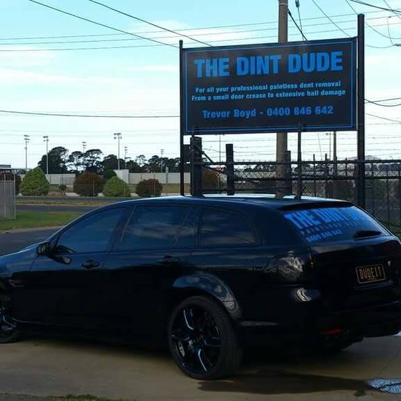 The Dint Dude sign reading Trevor Boyd 0400 846 642, with the black wagon parked below it