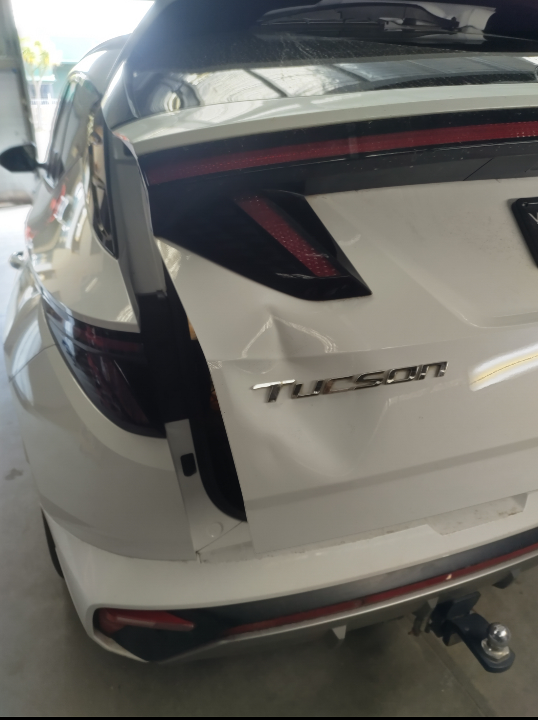 White Hyundai Tucson tailgate with a dent beside the Tucson badge